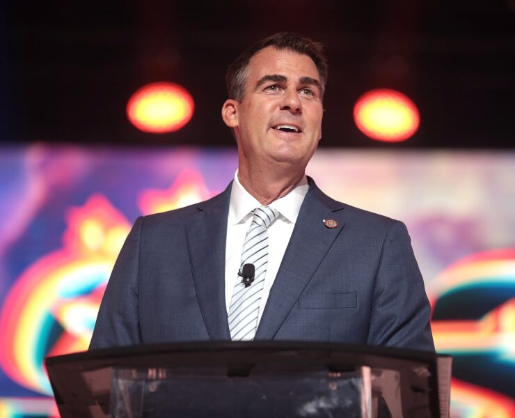 Kevin Stitt stands in front of a microphone.