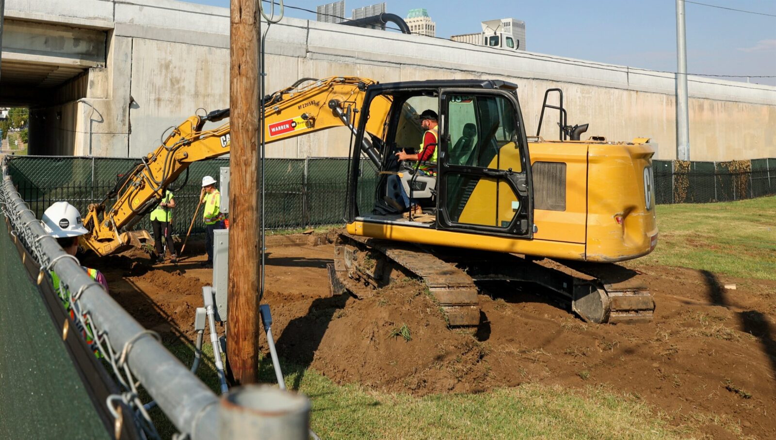 A man sits in an excavator and moves dirt in a cemetery